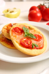 Plate with different tasty mini pizzas on white background