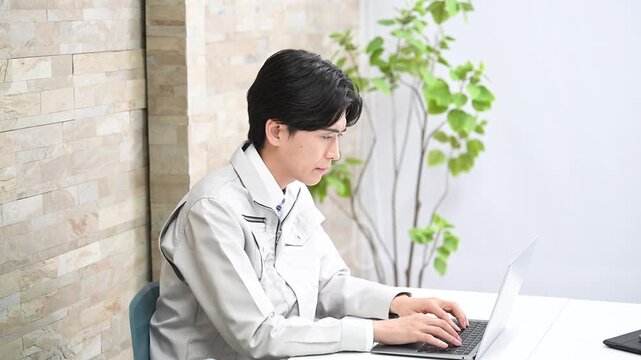 作業着で建築や施工などのパソコンの統計資料を作成するビジネスマンの動画