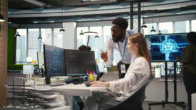 Cheerful startup manager satisfied with progress oj junior dev learning how to use machine learning tech. Team leader doing fist bump with intern in office, satisfied with work done, camera A