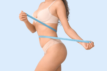 Beautiful young African-American woman with stretch marks on her body and measuring tape against...