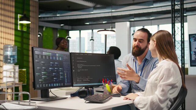 Friendly team leader helping happy young engineer code AI algorithms to debug software issues and improving system stability. Helpful manager assisting smiling intern in tech startup office, camera A