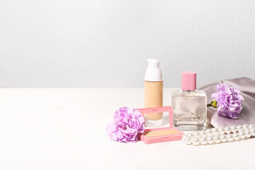 Makeup products with flowers, cloth and necklace on white background