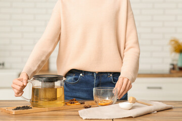 Young woman making green tea with spices in kitchen
