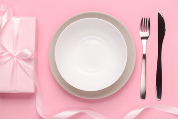 Festive table setting with present on pink background