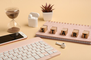 Cubes with text START, computer keyboard and mobile phone on beige background