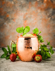 Refreshing Moscow mule cocktail with strawberries on the rustic background. Selective focus.