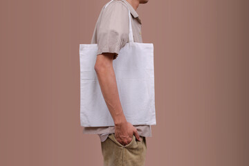 Close Up Of Young Male Consumer Using Blank White Eco Tote Bag, Posing Over Studio Background