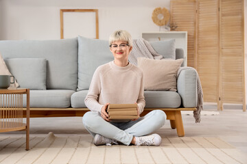 Young woman with short hair and books sitting on floor at home