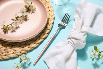 Beautiful table setting with blossoming branches on blue background