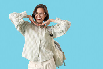 Happy female student with backpack showing tongue on blue background