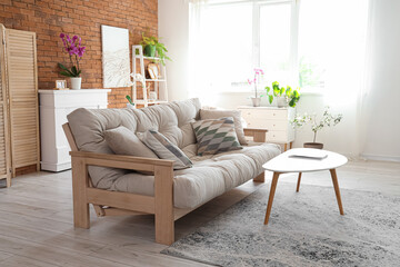 Interior of living room with sofa, table and orchid flower on fireplace