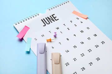 Calendar with office stationery on blue background, closeup