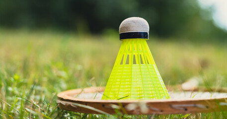 Badminton racket and shuttlecock lie on green grass. Outside recreation and fresh air. Healthy...