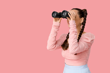 Beautiful young happy stylish woman with braids holding binoculars on pink background