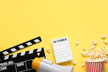 Calendar with movie clapper, megaphone and popcorn on yellow background