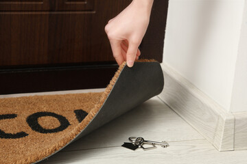Female hand with doormat and key on floor, closeup