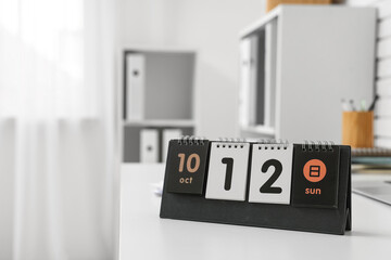 Flip calendar with date 12 OCTOBER on desk in office, closeup