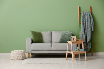 Comfortable sofa, ladder, table with calendar and books near color wall in room