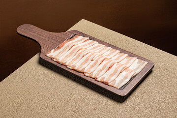 Thin-sliced frozen pork belly (Naeng-sam) sizzling on a hot grill. A popular Korean BBQ dish known...