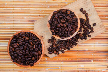 flat lay of roasted coffee beans in a wooden bowl on bamboo mat