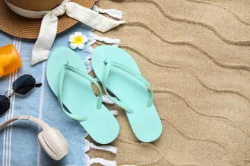 Composition with beach shoes, headphones and beach accessories on sand as background, closeup