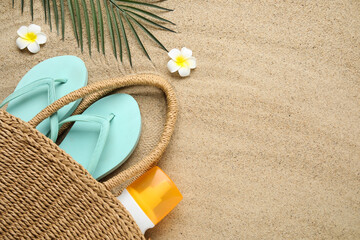 Composition with beach shoes, bottle of sunscreen cream and bag on sand as background, closeup