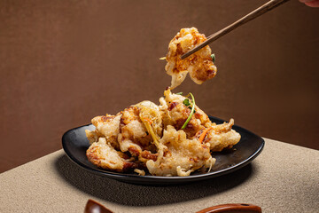 Sweet and sour Chinese pork (Guobaorou) held with chopsticks, showing crispy texture and glossy...