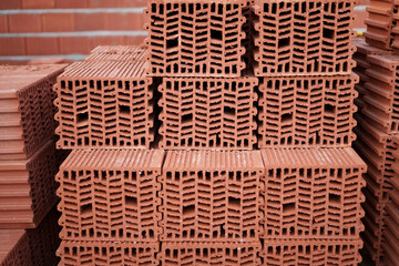 Hollow clay bricks neatly stacked on site, ready to shape the walls of a future energy-efficient...