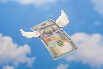 A hundred-dollar bill with small white wings. Money flying away, financial loss concept.