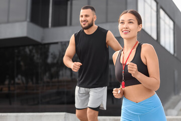 Female Asian personal trainer with man running outdoors
