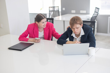 Caucasian Businesswoman Uses Smartphone While Colleague Has Problems At Work. 