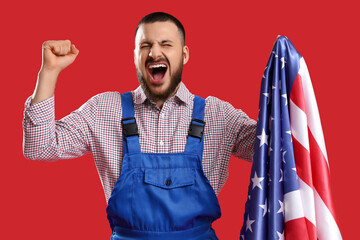 Happy male worker with USA flag on red background. Labor Day celebration