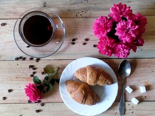 still life with coffee, croissants, pink roses on a wooden background, top view