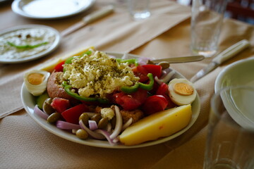 Colorful Mediterranean salad featuring fresh vegetables, boiled eggs, cheese, and olives on a...