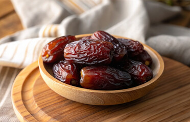 Dates in plate on wooden table in natural background