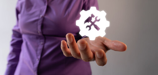 A businesswoman extends her hand with a white gear icon and a wrench symbol floating above it, representing the concept of service or support