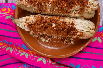 Top view of corn on the cob on a plate and Mexican pink tablecloth, Mexican food