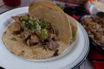 A photo of a plate of carnitas tacos with cilantro and onion salsa verde. Mexican food