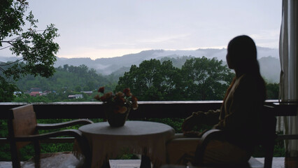 Blurred of a woman looking at a beautiful foggy mountain from wooden terrace