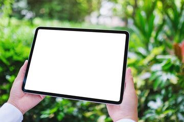 Mockup image of a woman holding digital tablet with blank white desktop screen in the nature...