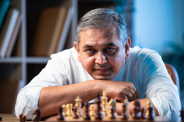 Indian executive focused on chess game at office desk, symbolizing corporate decision making