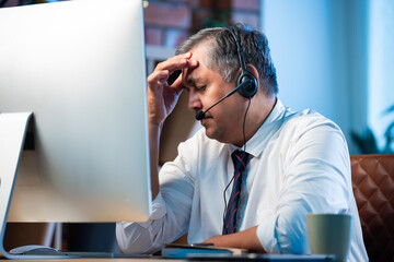 Stressed Indian support agent handling nonstop calls with headset in busy office