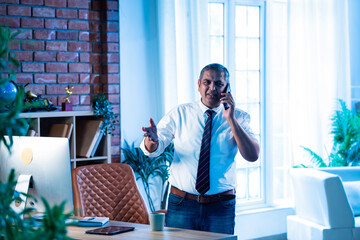 Indian executive multitasks with coffee and phone call inside contemporary office setting