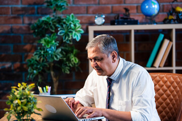 Indian executive working on laptop in a contemporary office environment with concentration