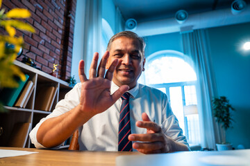 Confident Indian businessman on video call with client in stylish corporate office