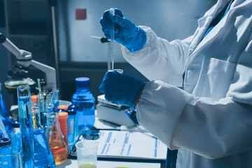 Scientist pipetting medical samples into microplate in laboratory