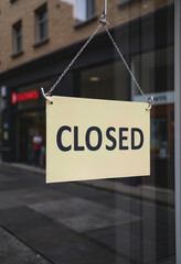Clearly Communicate Business Hours: A Simple Beige "CLOSED" Sign Hanging in a Shop Window, Indicating Temporary Closure or Off-Hours for a Storefront, Restaurant, or Cafe.
