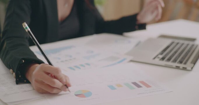 Close-up of businesswoman's hands checking data, graphs, statistical documents, preparing for team meeting
