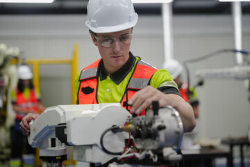 Smart Caucasian engineer working on AI technology in robotics electronics engineering laboratory. University students' research project is programming robot machine with intelligent mechanical control