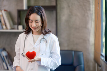 Asian female doctor holding a red heart in her hands in the concept of care your heart.